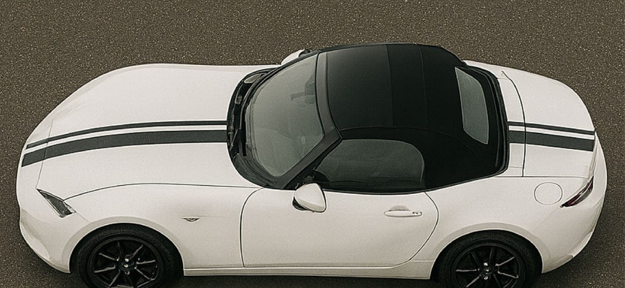 White car with black stripes and open door on a gray background